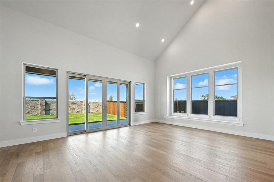 Unfurnished living room featuring high vaulted ceiling, light wood-style flooring, and recessed lighting Unfurnished living room featuring high vaulted ceiling, light wood-style flooring, and recessed lighting