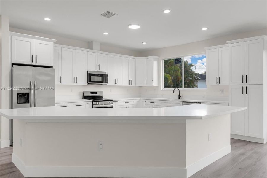 CUSTOM KITCHEN W/ CENTER ISLAND OVERLOOKING THE OPEN FLOOR PLAN LIVING ROOM.