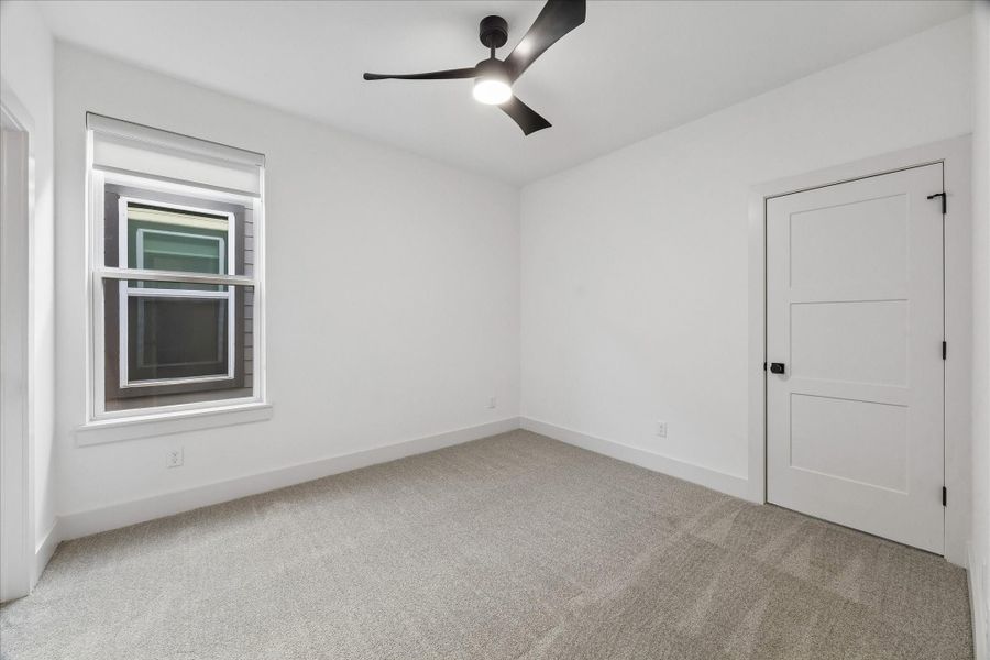 Comfortable secondary bedroom offers a flexible layout ideal for family, guests, or a private workspace. Soft neutral carpeting, a modern ceiling fan, and oversized trim create a clean, inviting atmosphere, while the generously sized closet and abundant natural light provide the functionality and comfort expected in every bedroom. Thoughtfully designed to accommodate a variety of needs, this space is both practical and welcoming.