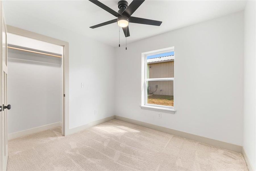 Unfurnished bedroom featuring light carpet, ceiling fan, and a closet Unfurnished bedroom featuring light carpet, ceiling fan, and a closet
