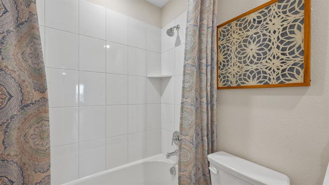 Full bath with shower / bath combination with curtain and a textured wall Full bath with shower / bath combination with curtain and a textured wall