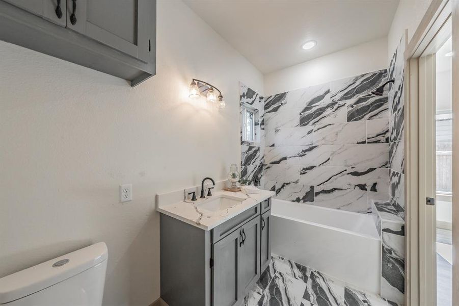 Full bath featuring light marble finish floors, vanity, shower / tub combo, and recessed lighting