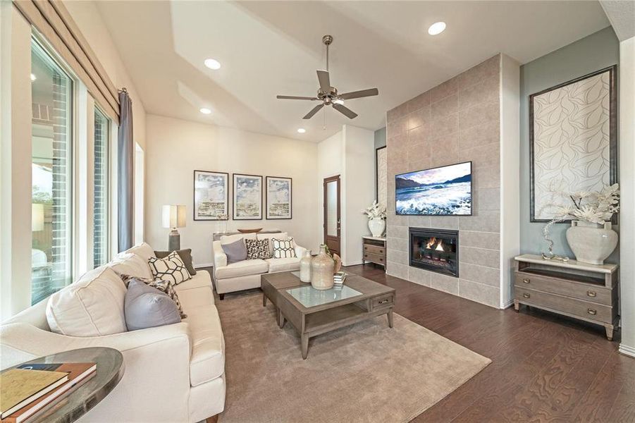 Vaulted ceiling living area featuring a tile-clad fireplace, dark wood-finish flooring, recessed lighting, and a ceiling fan