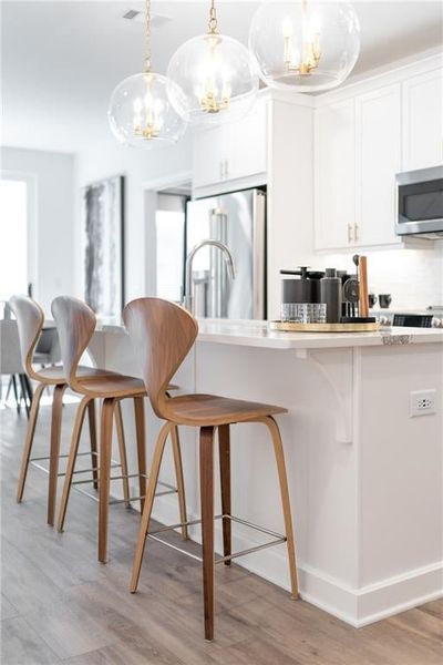 The kitchen island creates a great space for guests to sit and chat while dinner is being prepped. Not actual home. Photos of Model Home.