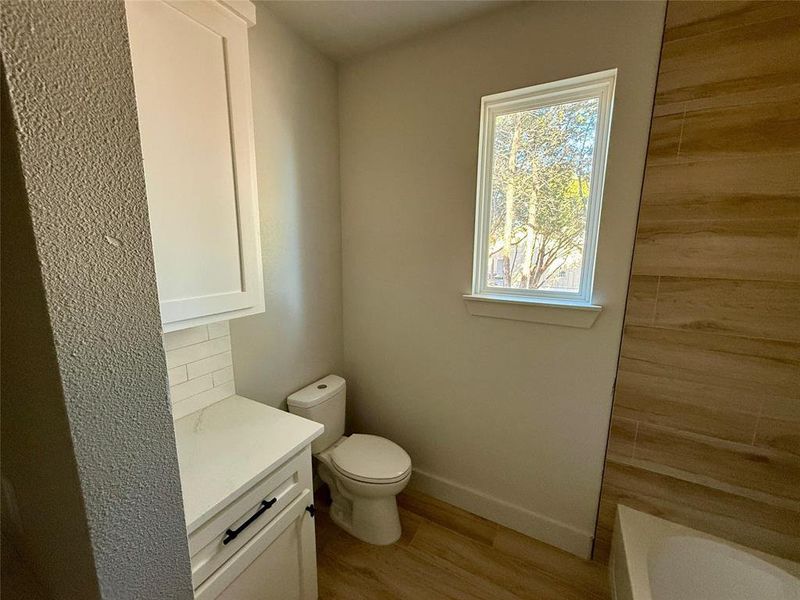 Guest Bathroom with vanity, light wood-type flooring, a bathtub, and backsplash