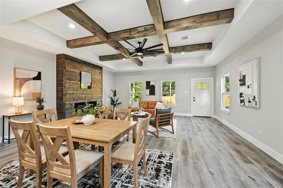 Dining area featuring a fireplace, light wood-style flooring, beamed ceiling, coffered ceiling, and a ceiling fan Dining area featuring a fireplace, light wood-style flooring, beamed ceiling, coffered ceiling, and a ceiling fan