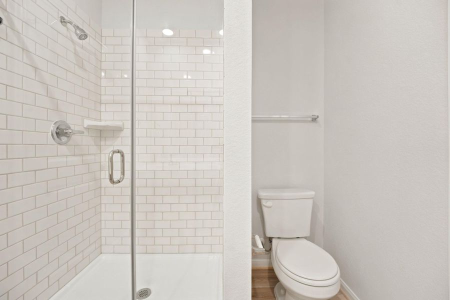 A glass-enclosed shower showcases clean white subway tile alongside a separate toilet alcove.