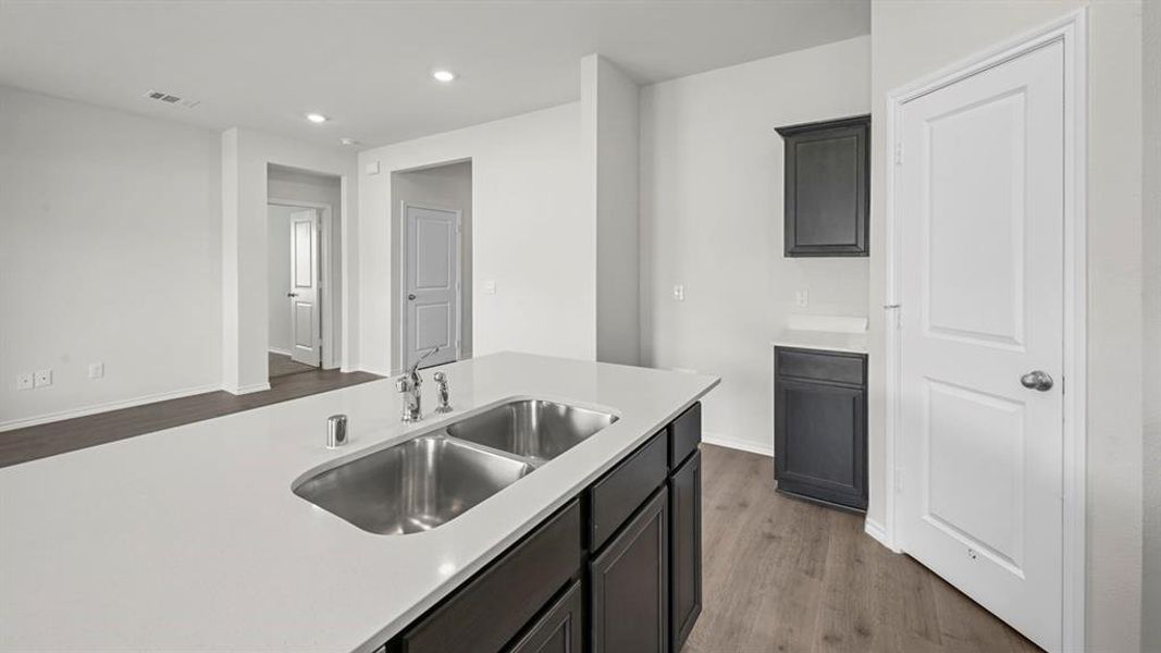 Kitchen with recessed lighting, dark wood finished floors, dark cabinets, and light stone counters