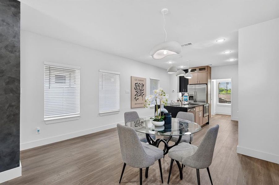 Open-concept dining area featuring wood-finish flooring, recessed lighting, and a kitchen with stainless steel appliances