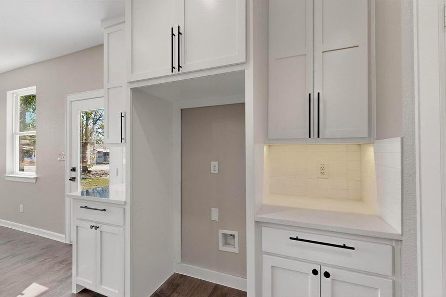 Kitchen with white cabinets, dark wood finished floors, and light stone countertops Kitchen with white cabinets, dark wood finished floors, and light stone countertops