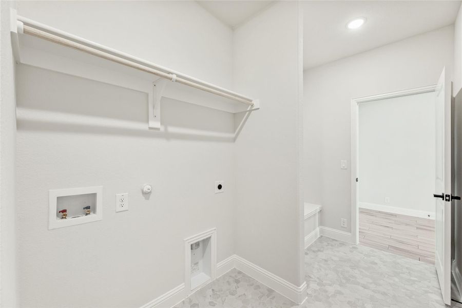 Laundry room with wall-mounted shelf, clothing rod, washer hookups, and tile floor