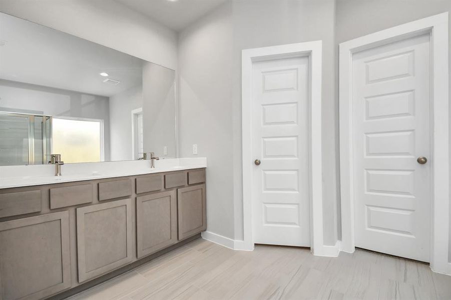 Escape to a spa-like oasis in this primary bathroom. Features an elegant vanity featuring light countertops, modern hardware, and bright recessed lights. Experience luxury and relaxation in every detail. Sample photo, as built color and selections will vary.