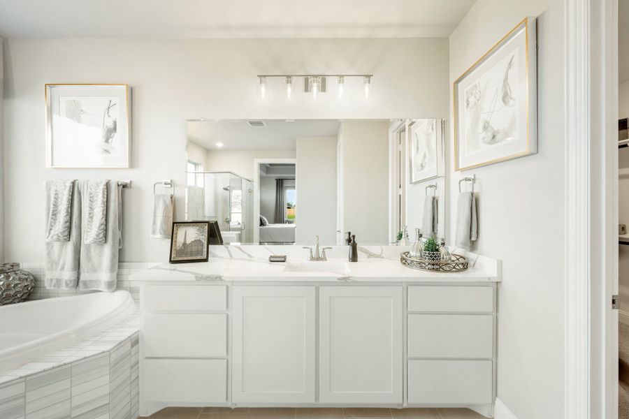 Bathroom with white vanity, large mirror, soaking tub, and light-colored tile floors Bathroom with white vanity, large mirror, soaking tub, and light-colored tile floors