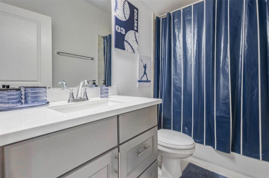 This bathroom features a modern design with a sleek white vanity and chrome faucet. It includes a combo tub-shower This bathroom features a modern design with a sleek white vanity and chrome faucet. It includes a combo tub-shower