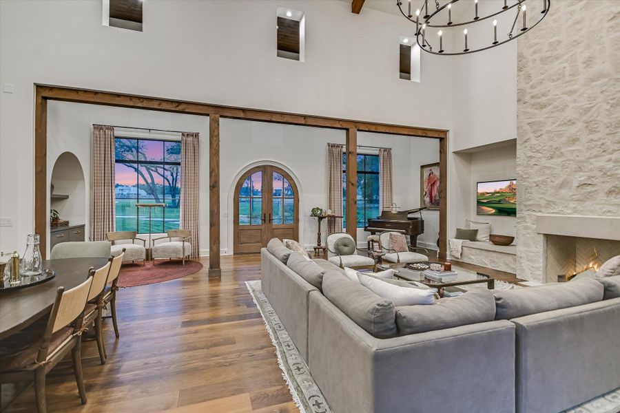 Living room featuring french doors, wood finished floors, a high ceiling, a fireplace, and a chandelier Living room featuring french doors, wood finished floors, a high ceiling, a fireplace, and a chandelier
