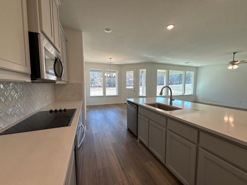 Kitchen featuring backsplash, dark wood-type flooring, stainless steel appliances, gray cabinets, and pendant lighting