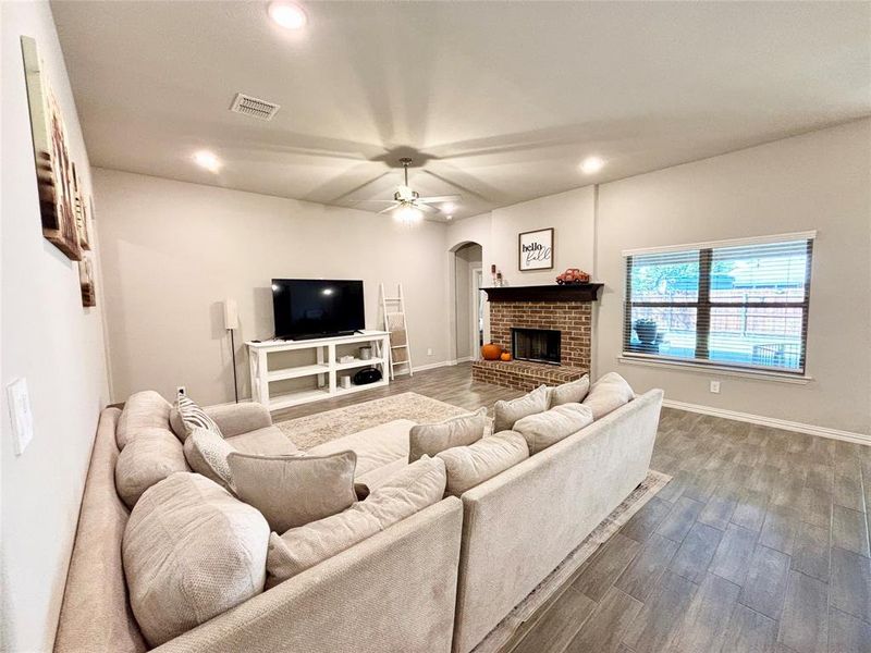 Living room featuring recessed lighting, a brick fireplace, wood finished floors, arched walkways, and ceiling fan Living room featuring recessed lighting, a brick fireplace, wood finished floors, arched walkways, and ceiling fan
