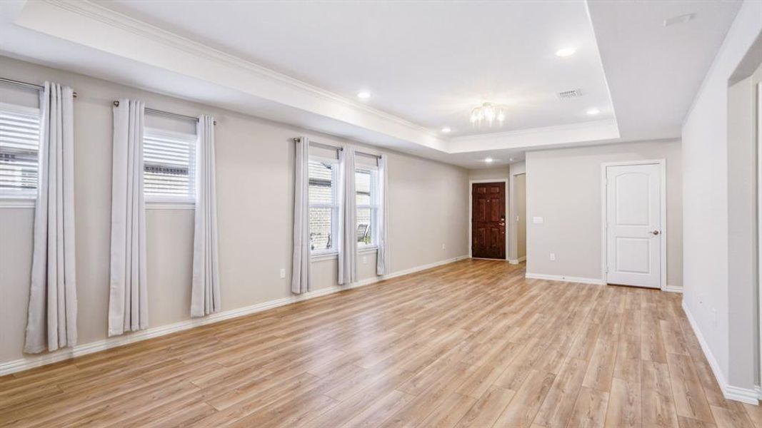 Empty room featuring a tray ceiling, crown molding, recessed lighting, and light wood-style floors Empty room featuring a tray ceiling, crown molding, recessed lighting, and light wood-style floors