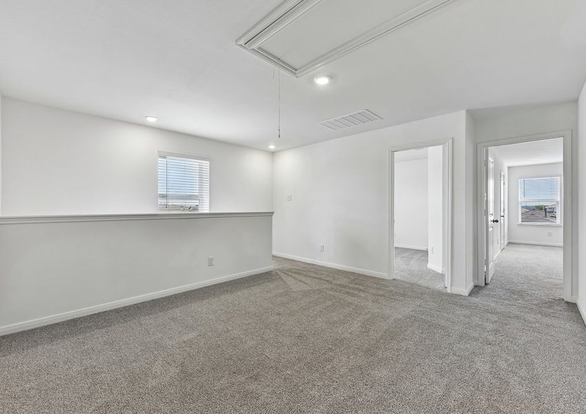 Open-concept game room featuring wood-look vinyl flooring, a window, and a sightline to the stair half wall.