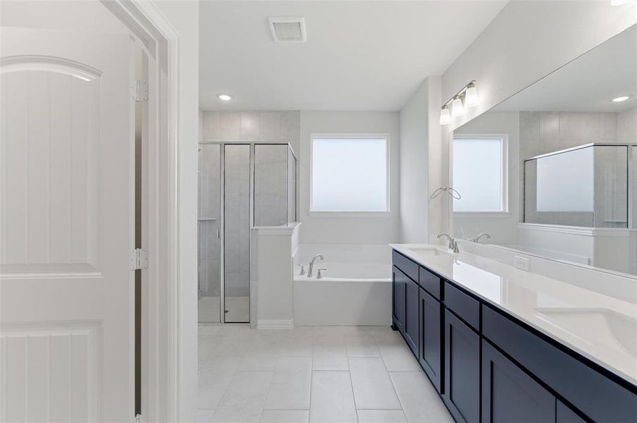 Spacious bathroom featuring a dual vanity with dark cabinetry, integrated rectangular sinks, and a large wall-mounted mirror