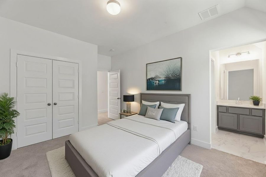 Bedroom featuring light colored carpet, a closet, and connected bathroom Bedroom featuring light colored carpet, a closet, and connected bathroom