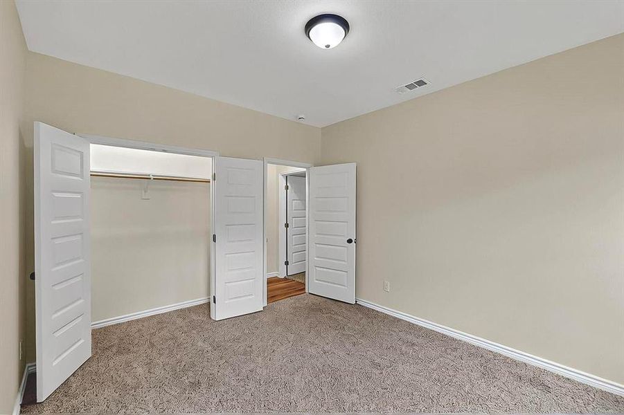 Unfurnished bedroom featuring baseboards, carpet, a closet, and visible vents Unfurnished bedroom featuring baseboards, carpet, a closet, and visible vents