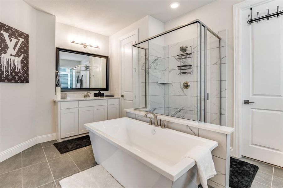Bathroom with a freestanding bath, light tile patterned floors, a stall shower, and vanity