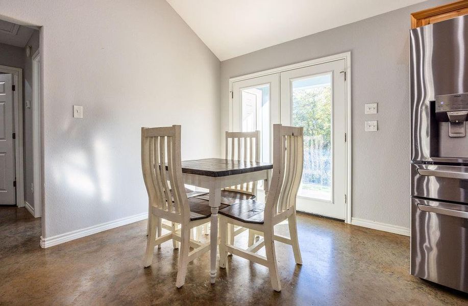 Dining room featuring finished concrete flooring, lofted ceiling, and french doors