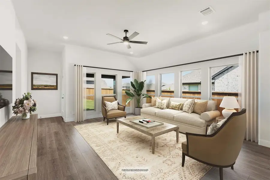 Living room with vaulted ceiling, ceiling fan, hardwood floors, and large windows with neutral furniture seating area. Living room with vaulted ceiling, ceiling fan, hardwood floors, and large windows with neutral furniture seating area.