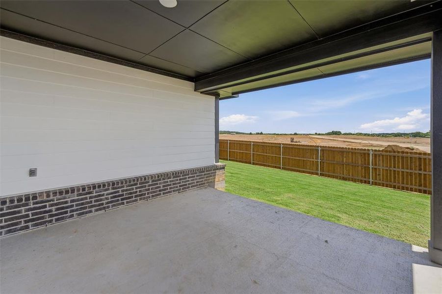 Covered patio featuring a concrete slab, white horizontal siding, and dark brick wainscoting Covered patio featuring a concrete slab, white horizontal siding, and dark brick wainscoting