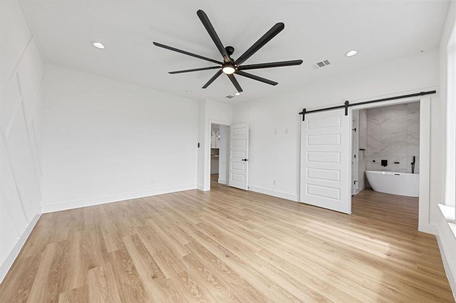 This expansive room features light wood flooring, a modern ceiling fan, and recessed lighting This expansive room features light wood flooring, a modern ceiling fan, and recessed lighting