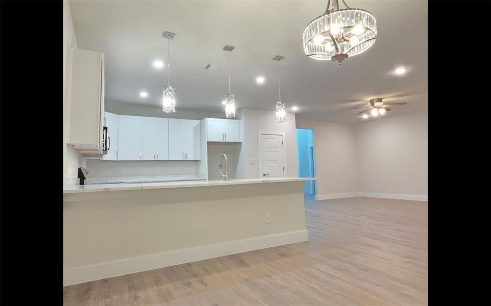 Dining room overlooking kitchen, designer chanderliers, white quartz countertops, overlooking living room