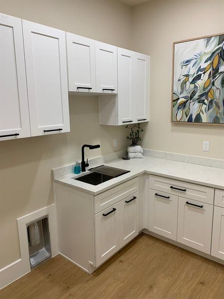 Kitchen featuring light  , sink, and white cabinets