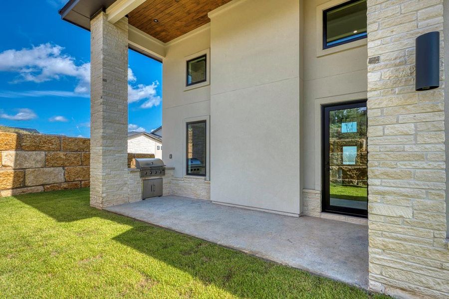 Concrete patio details include a built-in outdoor grill area flanked by modern stone columns. Concrete patio details include a built-in outdoor grill area flanked by modern stone columns.