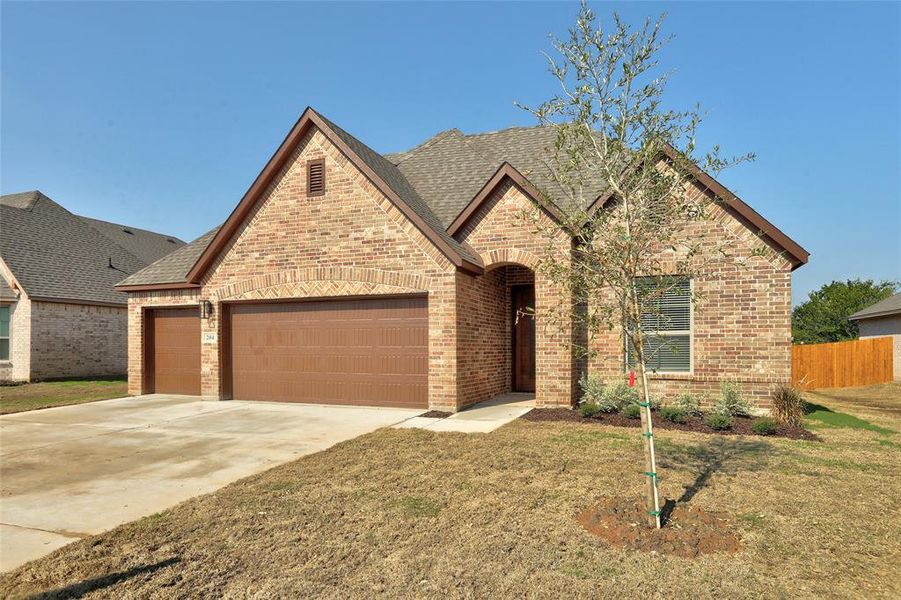 French provincial home with brick siding, driveway, a shingled roof, and a garage