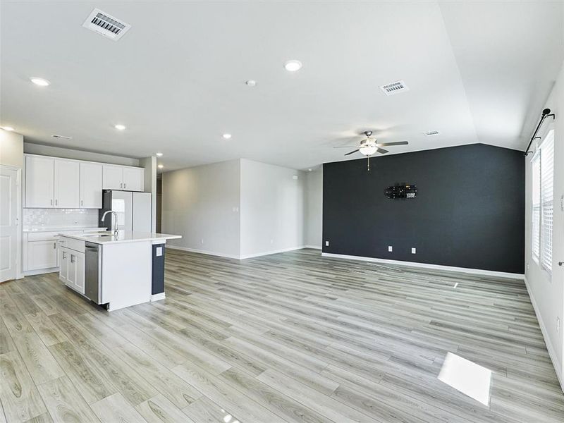 Kitchen with white cabinetry, dishwasher, backsplash, white fridge, and a center island with sink