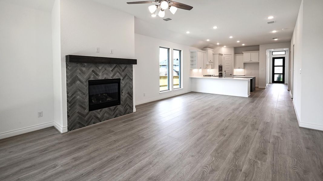Unfurnished living room with a tiled fireplace, dark wood finished floors, recessed lighting, and a ceiling fan Unfurnished living room with a tiled fireplace, dark wood finished floors, recessed lighting, and a ceiling fan
