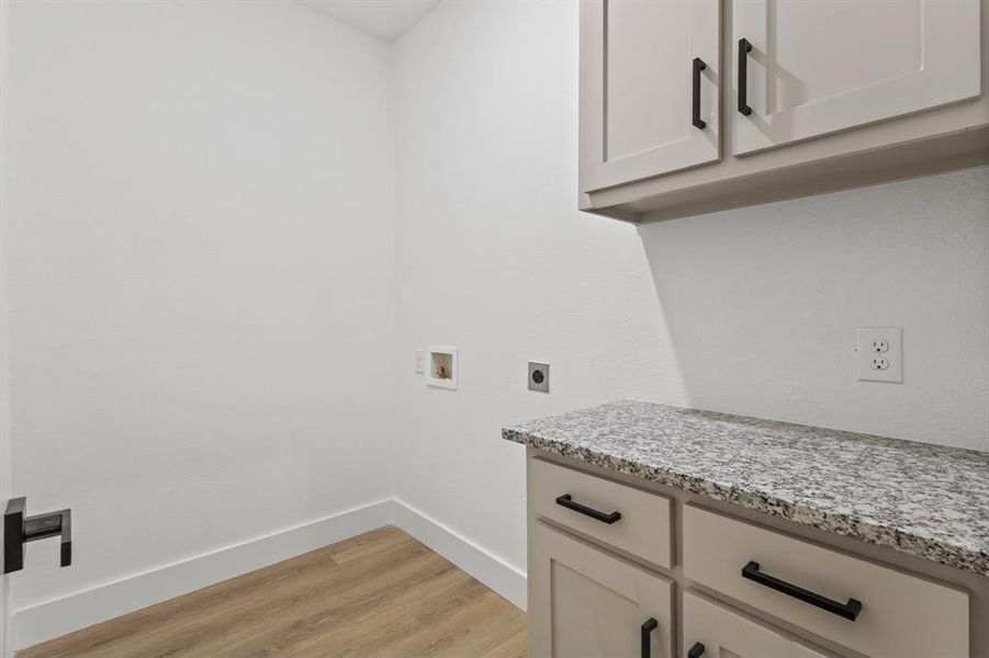 Laundry room featuring hookup for a washing machine, baseboards, cabinet space, electric dryer hookup, and light wood-type flooring