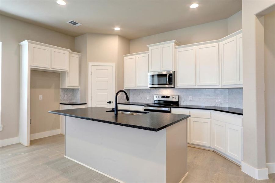 Kitchen featuring white cabinetry, appliances with stainless steel finishes, sink, and a center island with sink