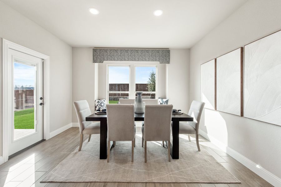 Dining room with dark rectangular table, six gray chairs, and backyard-facing windows and door Dining room with dark rectangular table, six gray chairs, and backyard-facing windows and door