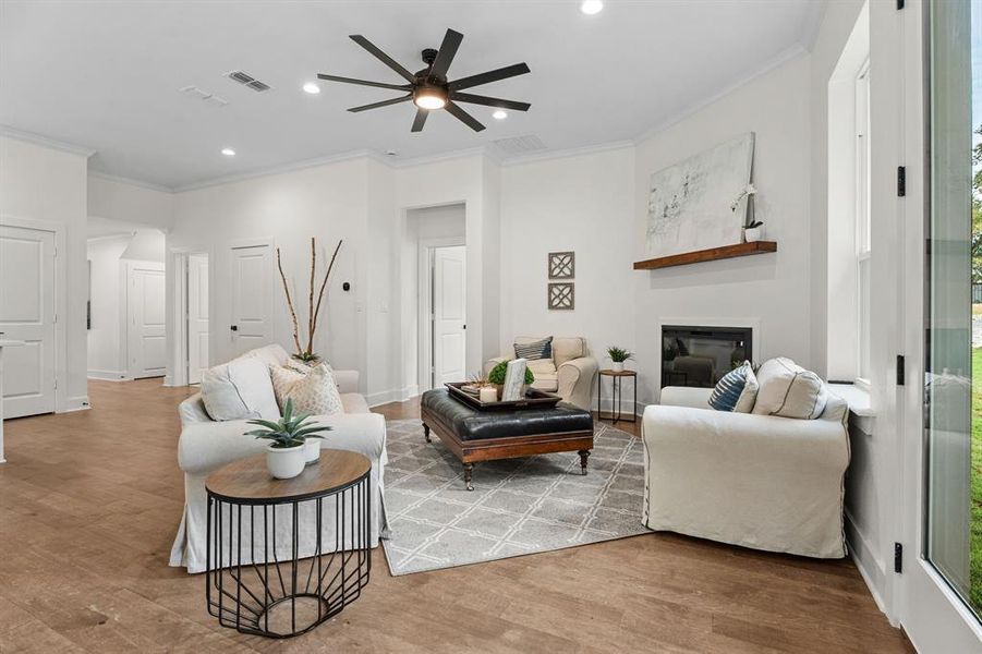 Living room with crown molding, wood-type flooring, and ceiling fan Living room with crown molding, wood-type flooring, and ceiling fan