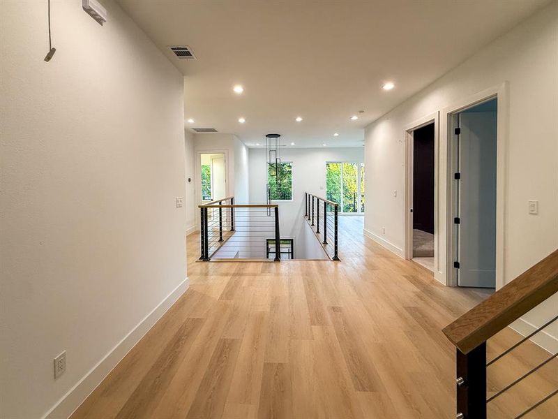 Hallway with an upstairs landing, recessed lighting, and light wood-style floors