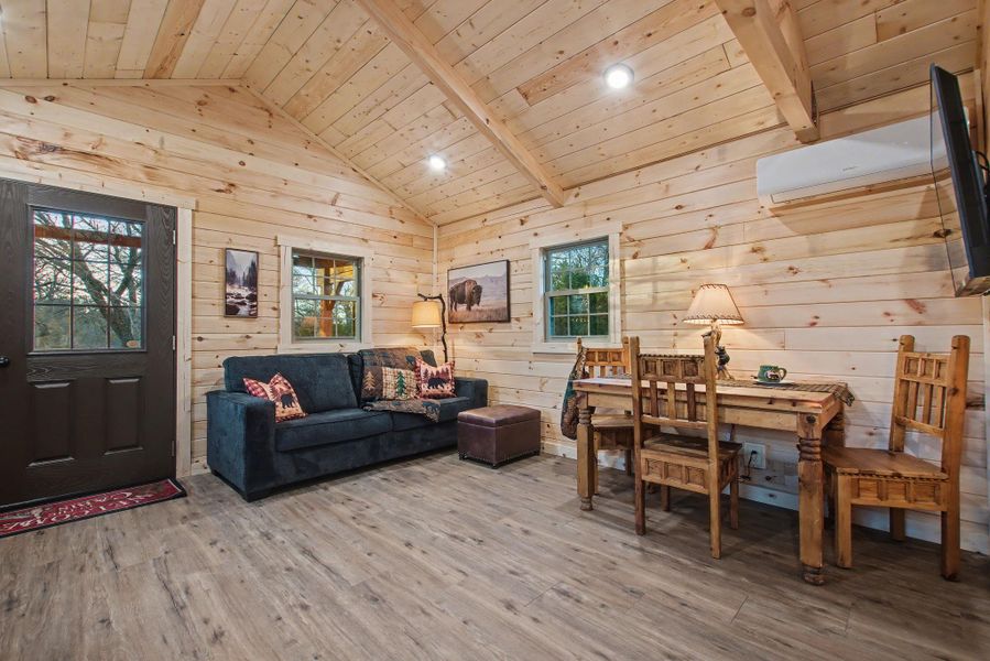 Living room with wooden ceiling, light wood-style flooring, wood walls, recessed lighting, and a wall mounted AC