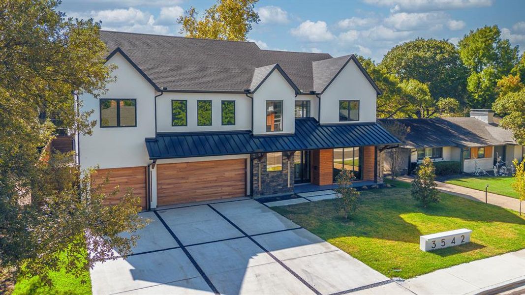 View of front facade with a porch, a standing seam roof, a front yard, driveway, and a metal roof View of front facade with a porch, a standing seam roof, a front yard, driveway, and a metal roof
