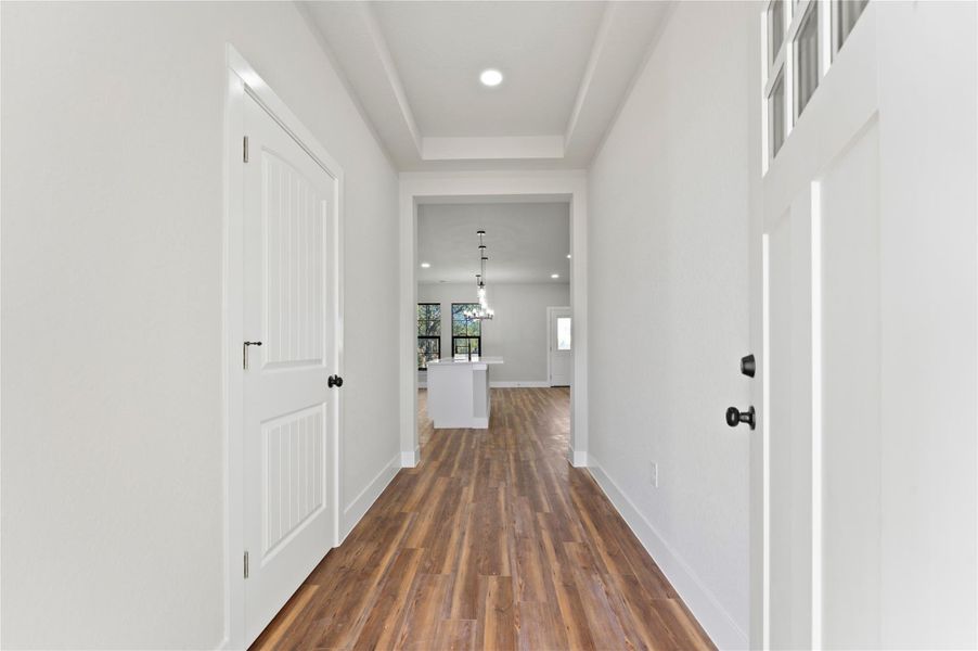 Hallway with recessed lighting, dark wood-style flooring, and a tray ceiling