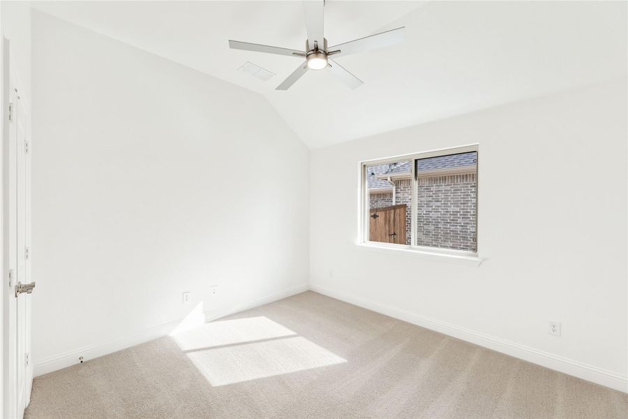 Empty bedroom with vaulted ceiling, ceiling fan, carpet flooring, and single window Empty bedroom with vaulted ceiling, ceiling fan, carpet flooring, and single window