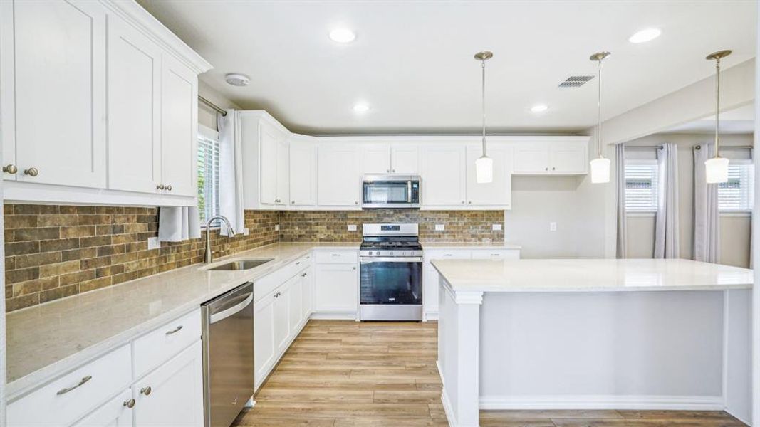 Kitchen with stainless steel appliances, pendant lighting, light stone countertops, white cabinets, and recessed lighting Kitchen with stainless steel appliances, pendant lighting, light stone countertops, white cabinets, and recessed lighting