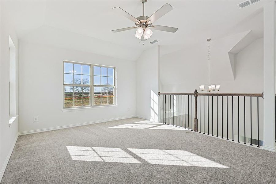 Carpeted spare room with ceiling fan, suspended lighting, and lofted ceiling