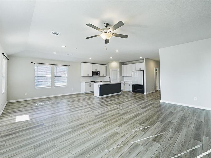 Unfurnished living room with ceiling fan, light hardwood / wood-style floors, and sink