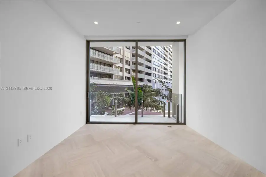 Herringbone wood-finish flooring, floor-to-ceiling sliding glass doors, and recessed lighting